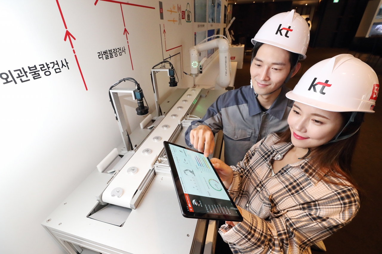 모델들이 KT 5G 스마트팩토리 상품을 보여주는 미니 제조 공정라인을 소개하고 있다. [사진=KT]