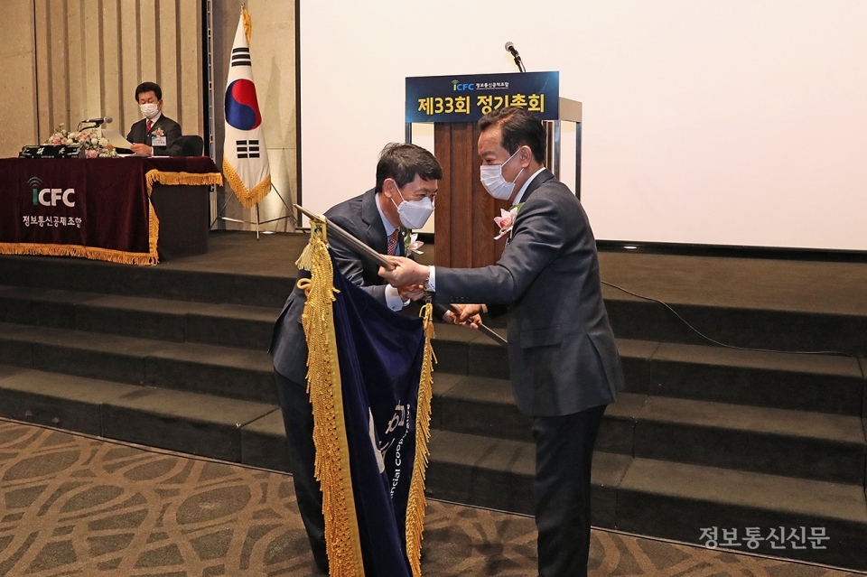 이재식 신임 이사장이 이명규 이사장으로부터 조합기를 전달받고 있다.